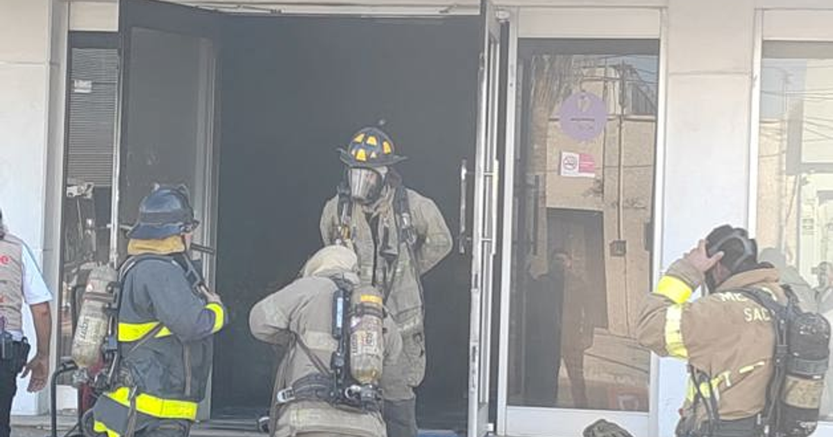 Bomberos de Los Mochis trabajando en la entrada de un edificio tras un incendio en un restaurante de sushi.