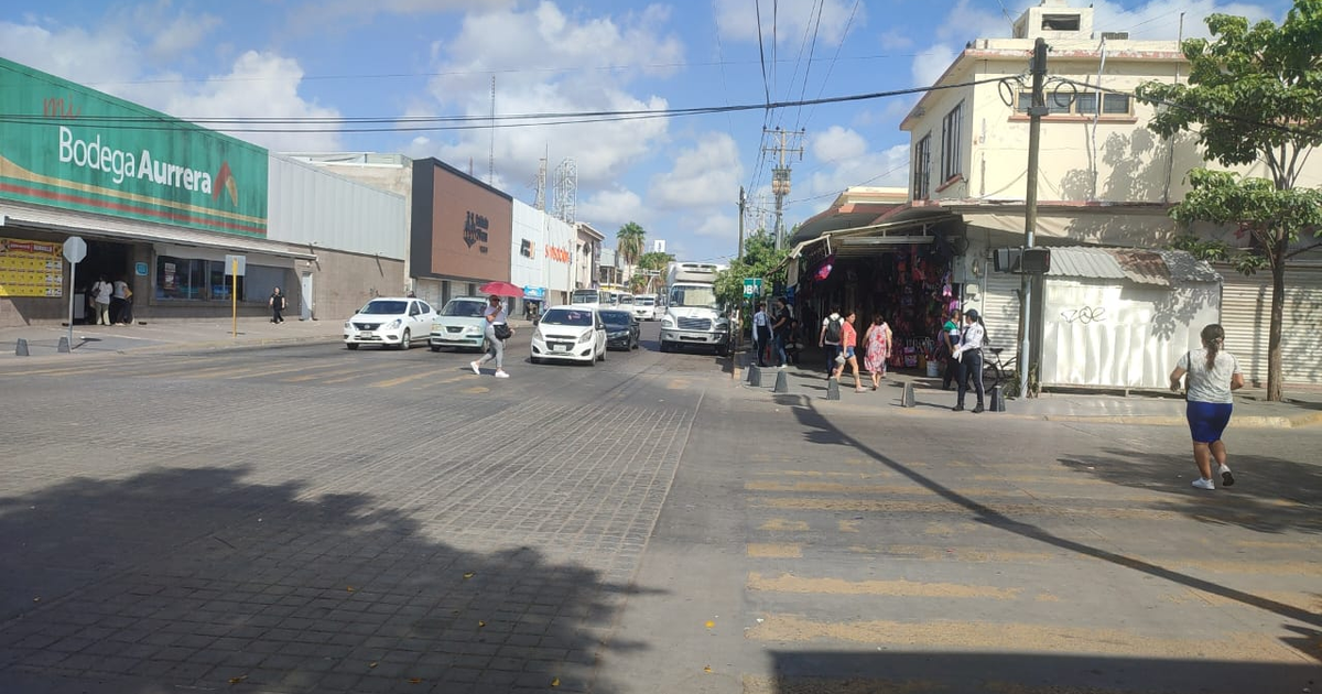 Calle en Los Mochis con Bodega Aurrera, vehículos y peatones bajo cielo nublado.