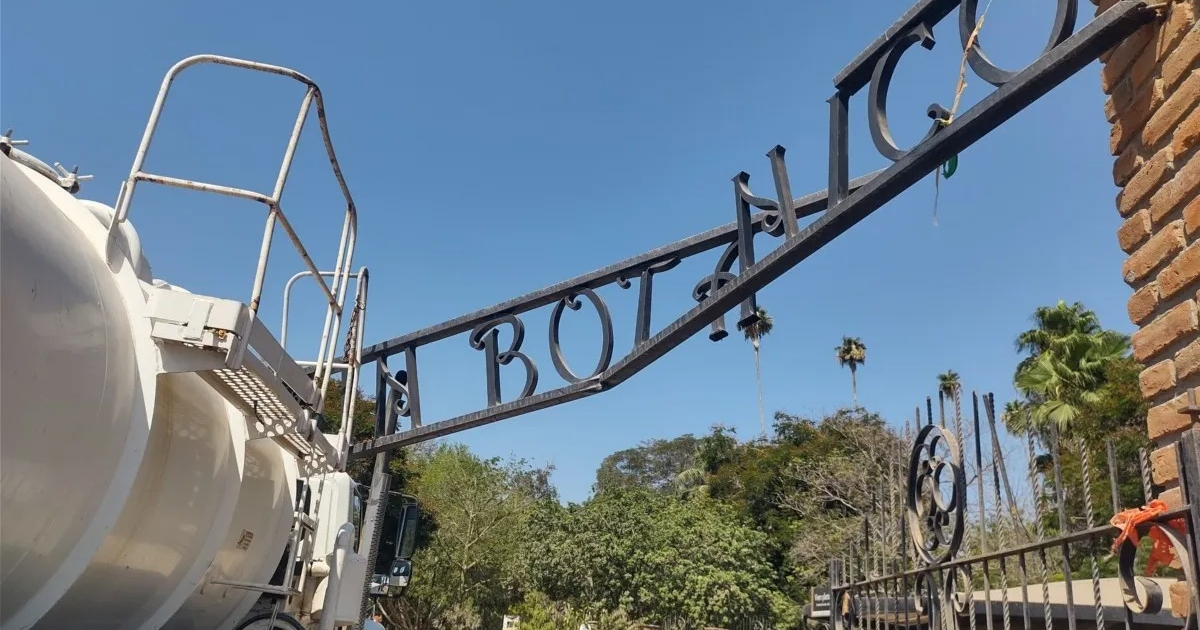 Estructura metálica con la palabra 'BOTÁNICO' en el Jardín Botánico Parque Sinaloa, con un tanque industrial al lado y cielo despejado.