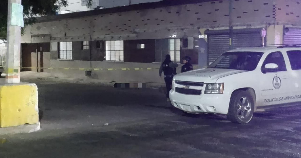 Operativo policial nocturno en área urbana con vehículo de investigación y agentes cerca de cordón de seguridad.