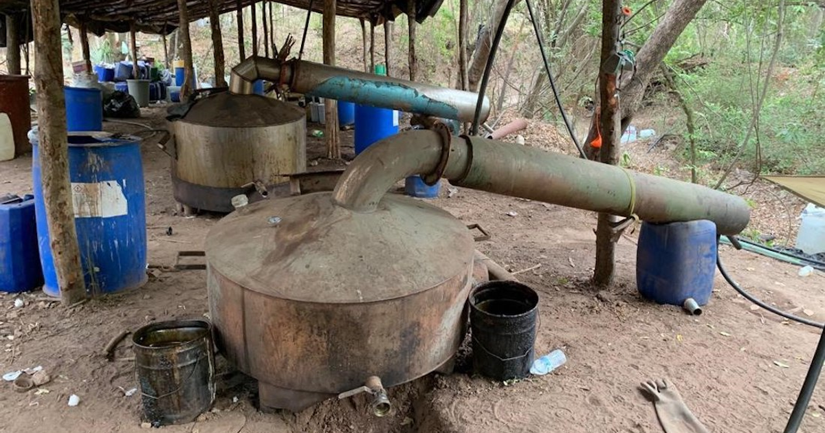 Entorno industrial al aire libre con calderas y barriles, vinculado a laboratorios móviles clandestinos en Culiacán.