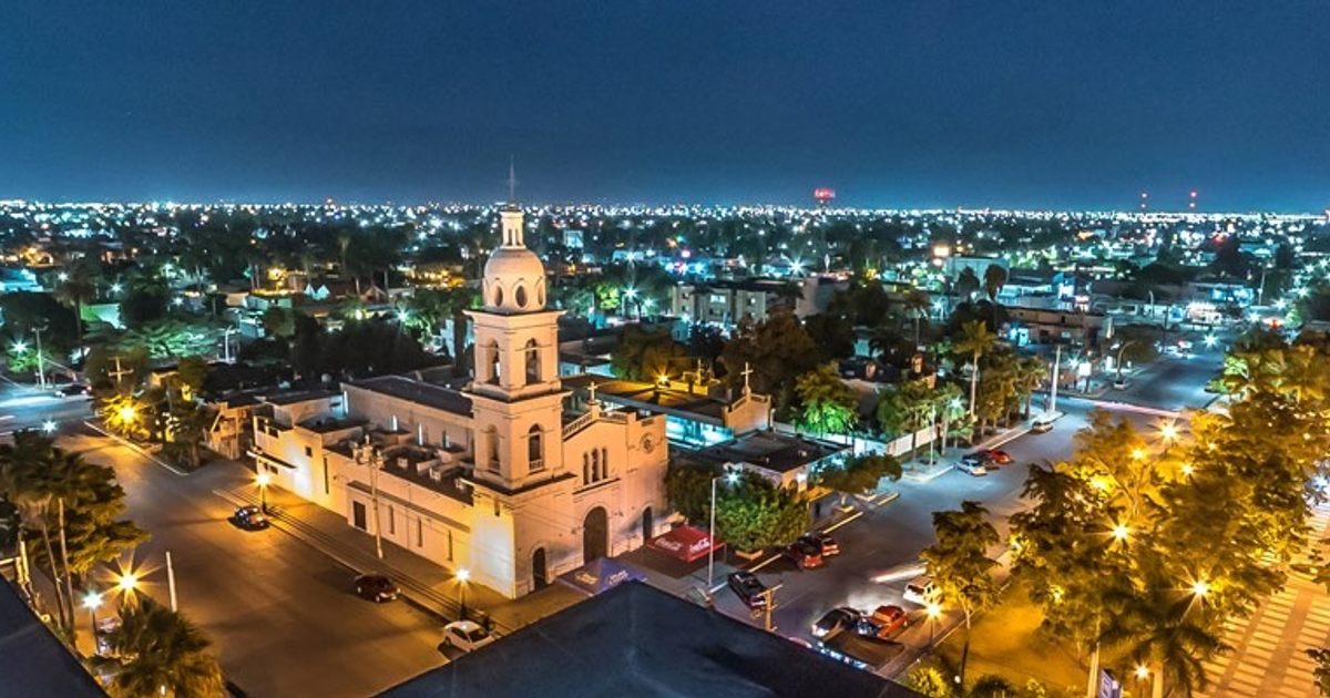 Vista nocturna de Los Mochis con edificio iluminado y luces urbanas