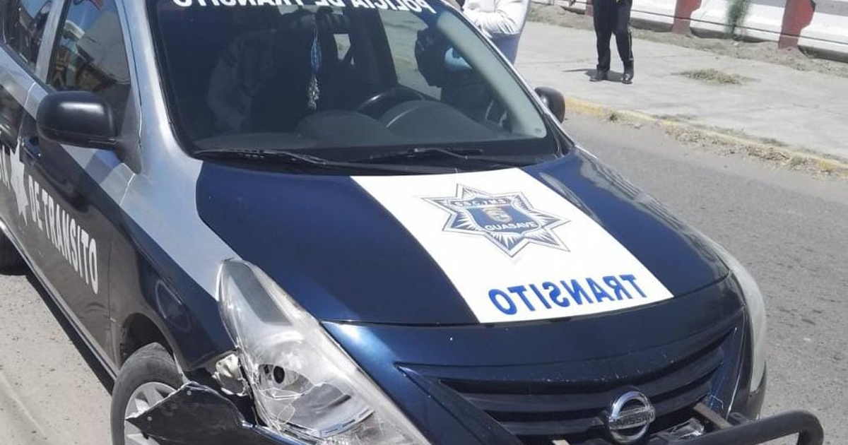 Coche patrulla de tránsito azul y plata con daños en el faro, rodeado de agentes de policía.