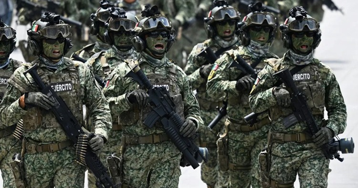 Soldados marchando en desfile militar con uniformes camuflados y rifles.