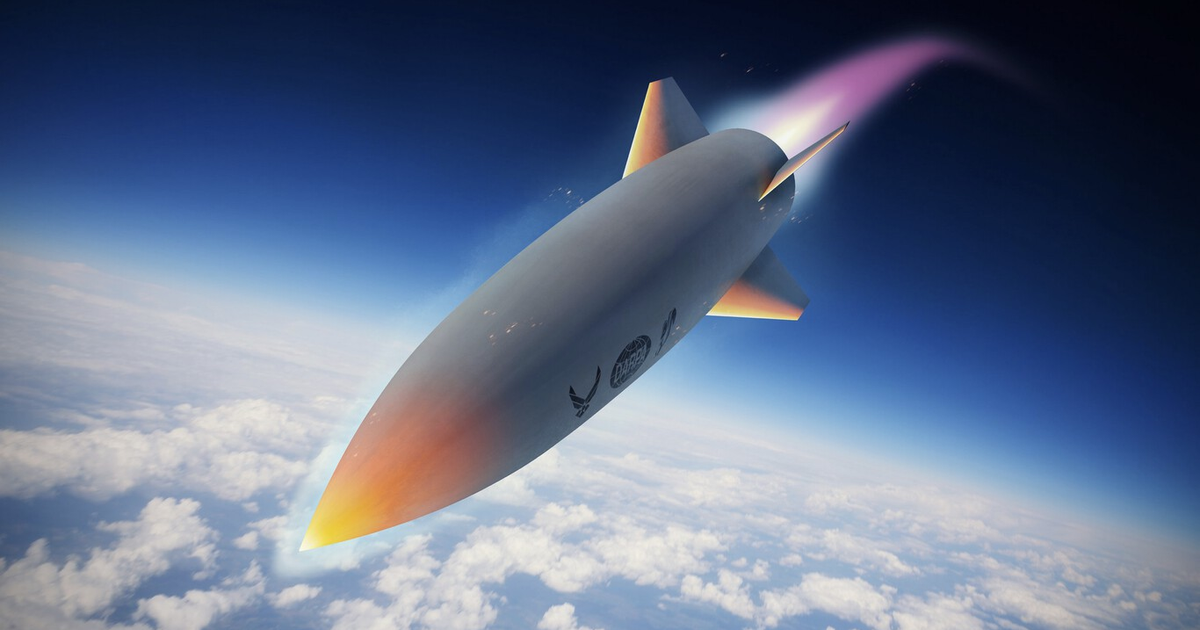 Misil hipersónico en el espacio con estela de humo, fondo azul y nubes.