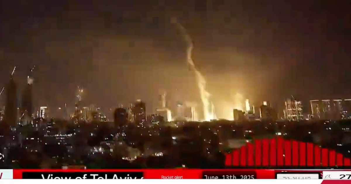 Paisaje nocturno de Tel Aviv con luces urbanas y fenómeno en el cielo, relacionado con impacto de misiles.