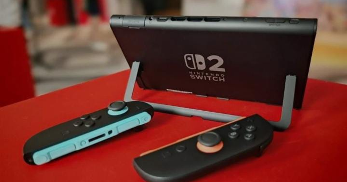 Consola Nintendo Switch 2 con controladores azul y negro sobre superficie roja