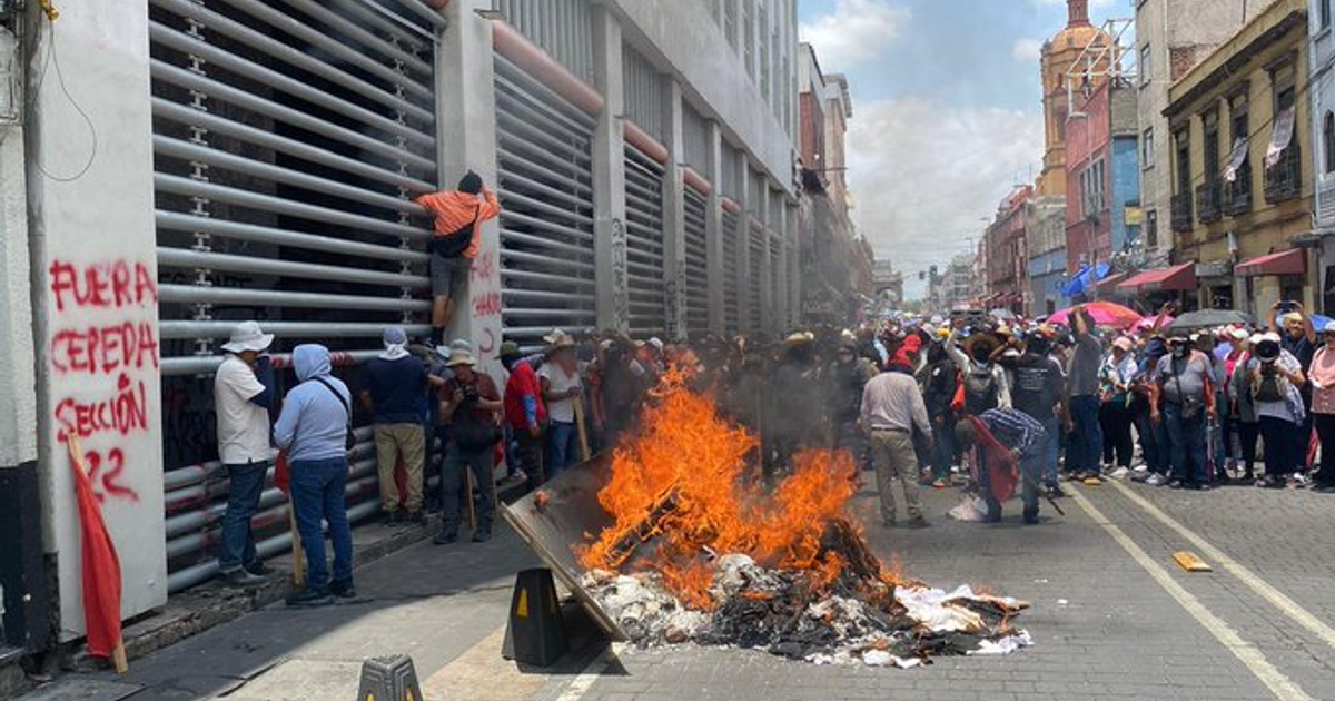 Protesta de maestros disidentes en la sede del SNTE con hoguera y grafitis políticos.
