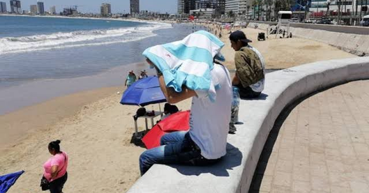 Playa de Mazatlán con oleaje elevado y personas disfrutando del sol