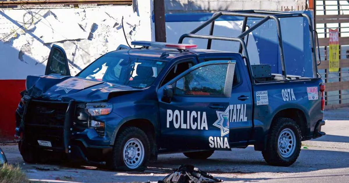 Camioneta de policía estatal dañada con puerta abierta y abolladuras en el frente, en un entorno urbano deteriorado.