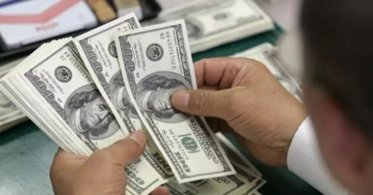 Manos contando billetes de cien dólares con más billetes apilados detrás, relacionado con la cotización del dólar en Sinaloa.