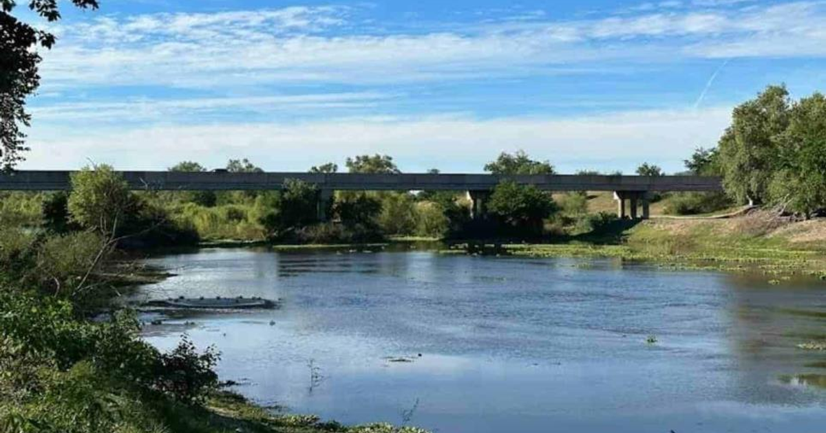 Paisaje natural con río y puente en Sinaloa, rodeado de vegetación y cielo parcialmente nublado.