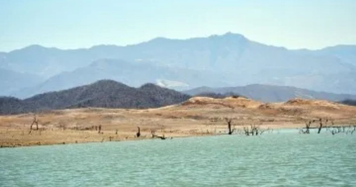 Vista de un cuerpo de agua en Sinaloa rodeado de montañas y áreas secas, reflejando la situación de los embalses según Conagua.