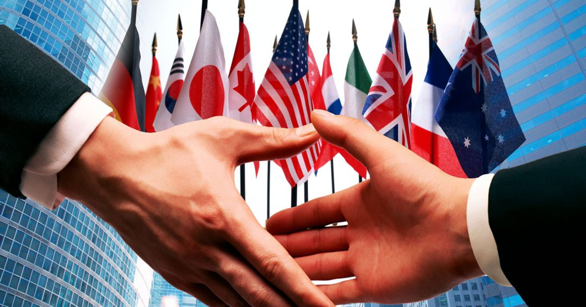 Apretón de manos frente a banderas internacionales simbolizando un acuerdo global