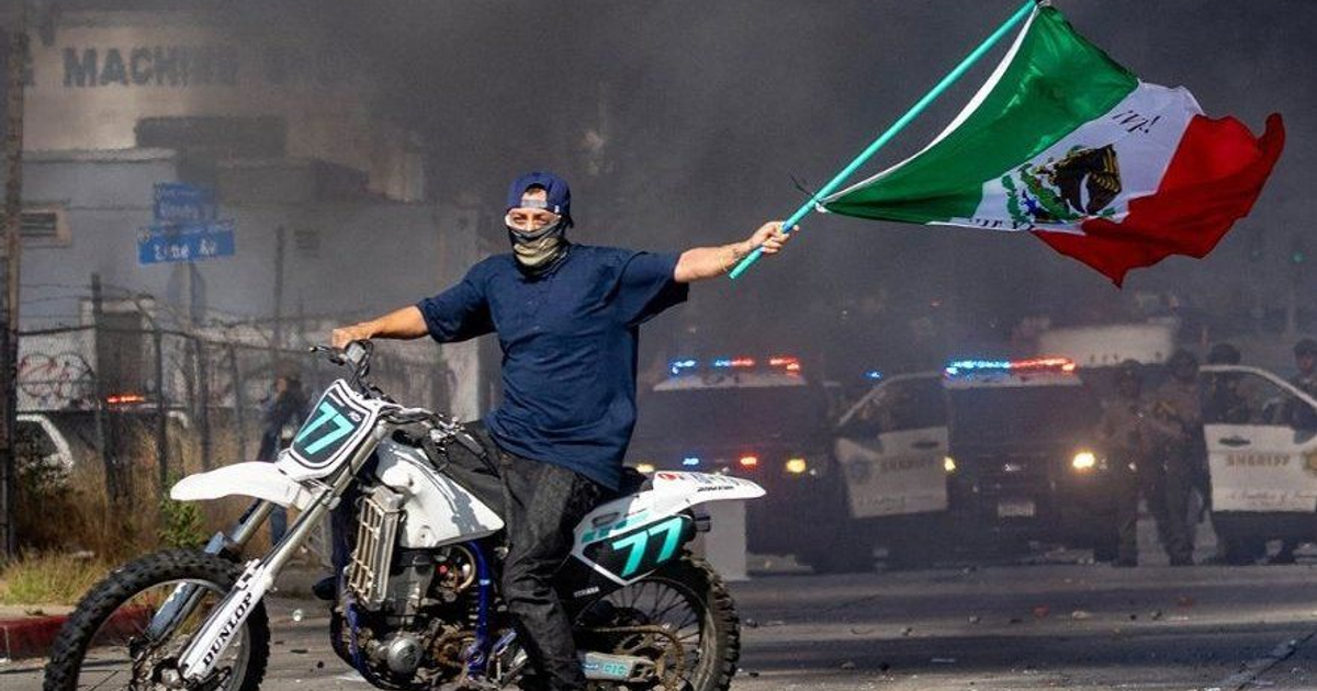 Manifestante en motocicleta con bandera de México en disturbios de Los Ángeles
