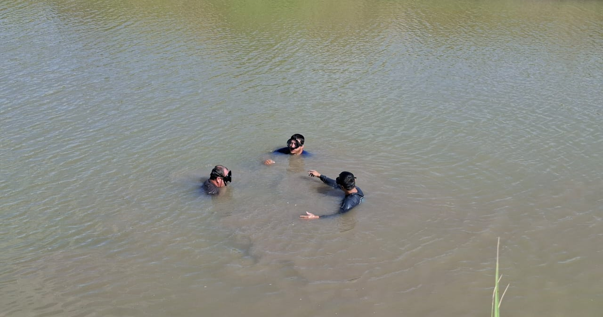 Tres personas en el agua marrón claro del canal alto de Guasave, Sinaloa, interactuando y explorando.