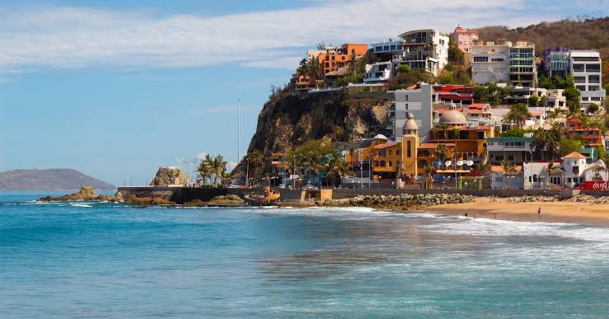 Playa de Mazatlán con edificios en colina y palmeras, en contexto de sanciones por lavado de dinero.