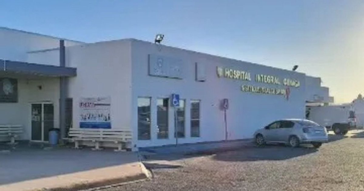 Vista exterior del Hospital Integral de Ojinaga, con bancas y un vehículo estacionado bajo la luz del sol.