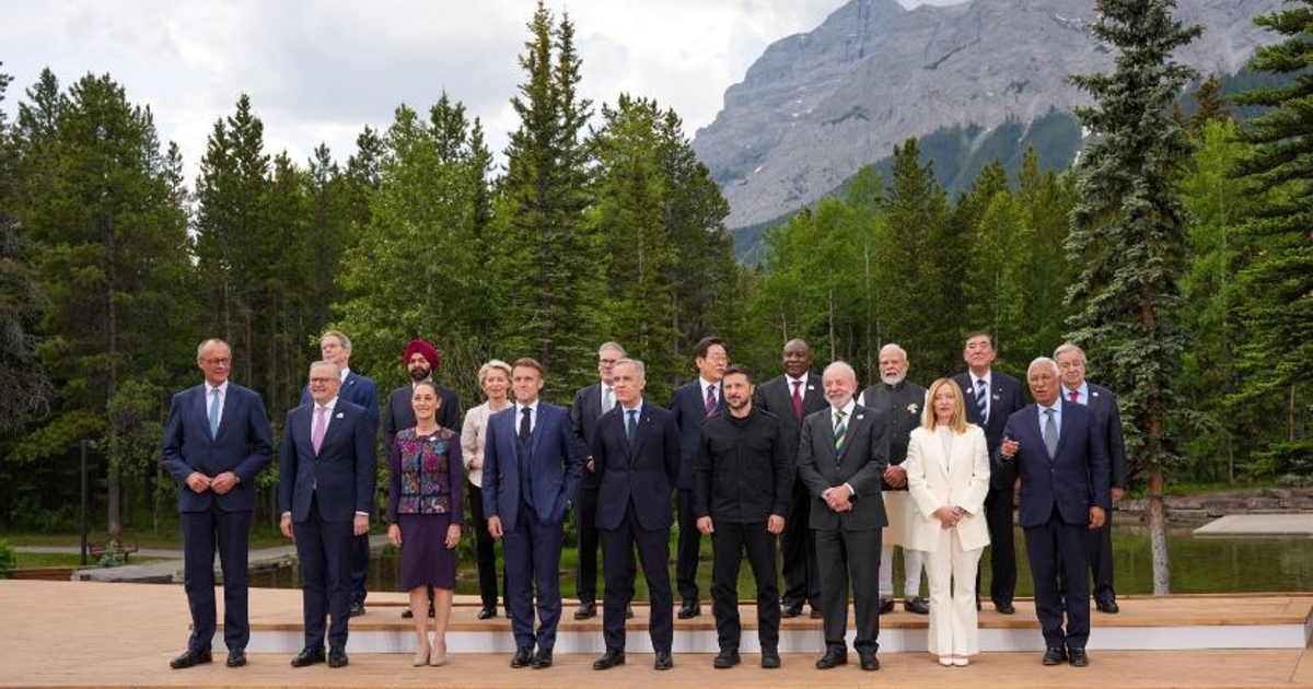 Líderes mundiales posan en la Cumbre del G7 con montañas y árboles de fondo.