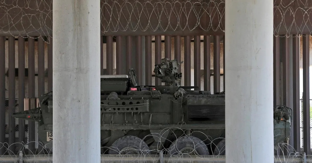 Vehículo blindado Stryker estacionado bajo estructura con columnas en área restringida.