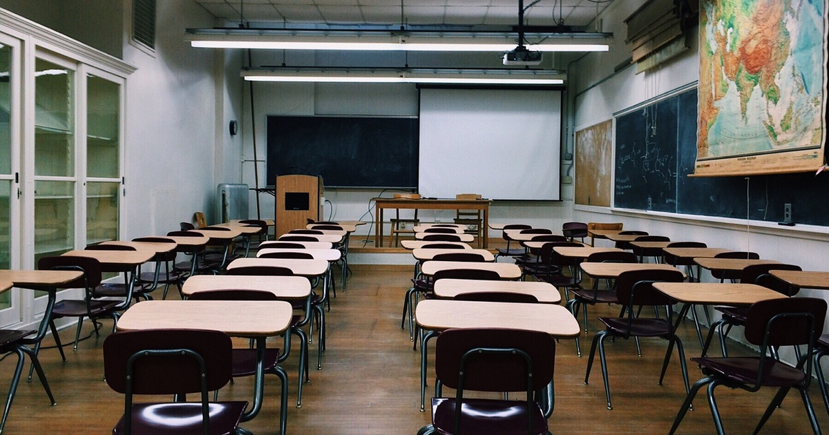 Aula vacía con mesas, sillas, proyector y pizarra, relacionada con la suspensión de clases en San Ignacio y Coyotitán.