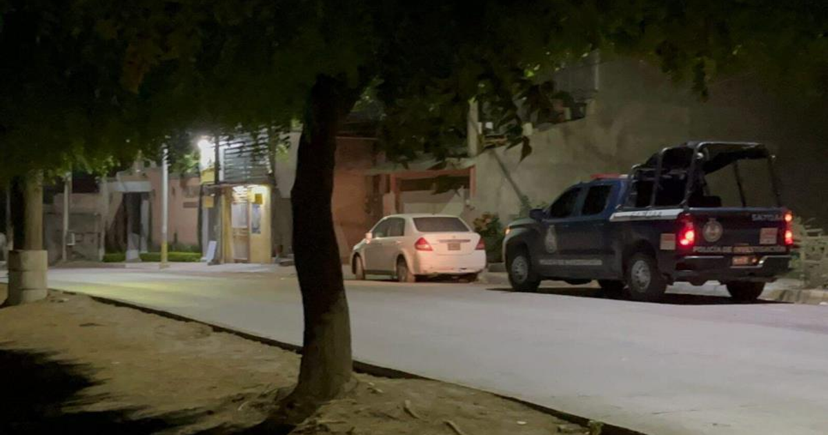 Calle nocturna en Mazatlán con coche blanco y camioneta de policía, escenario de un ataque armado.