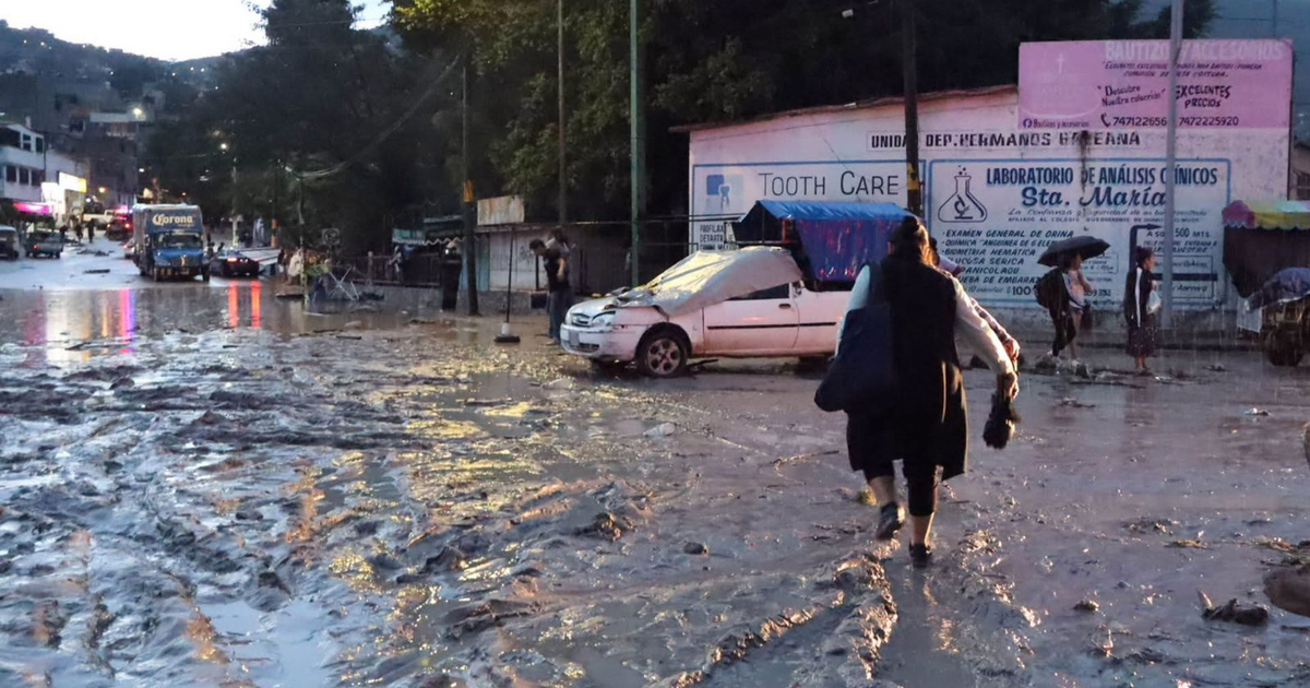 Calle inundada con vehículo sumergido y camión de 'Corona' durante tormenta Flossie
