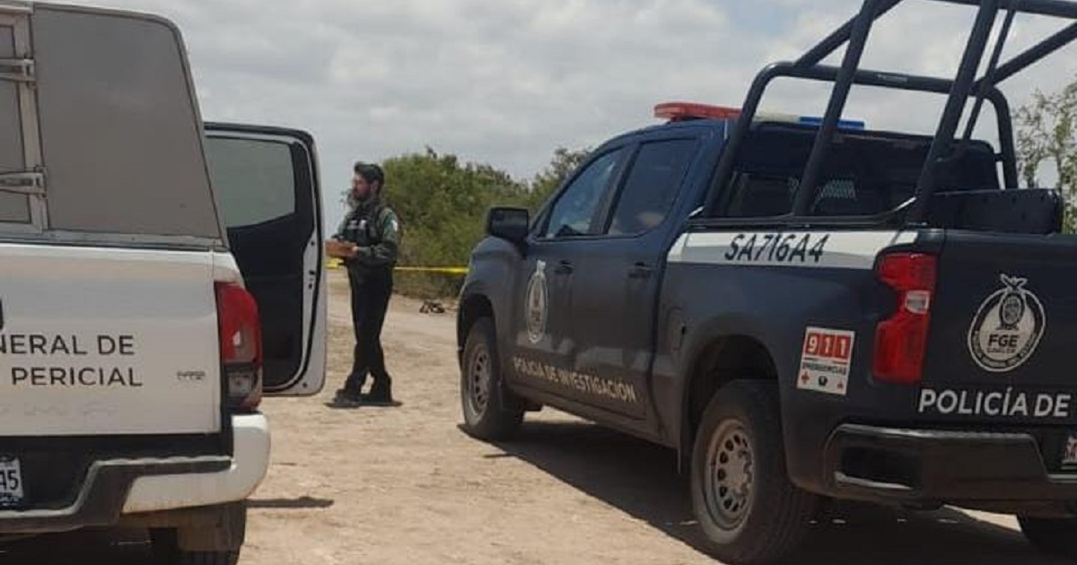 Vehículos policiales y oficial en investigación de triple homicidio en Navolato