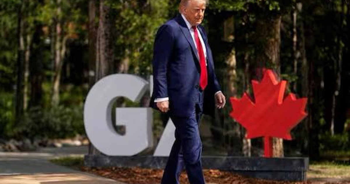 Persona caminando cerca de un letrero 'G7' con hoja de arce roja, simbolizando la cumbre en Canadá.