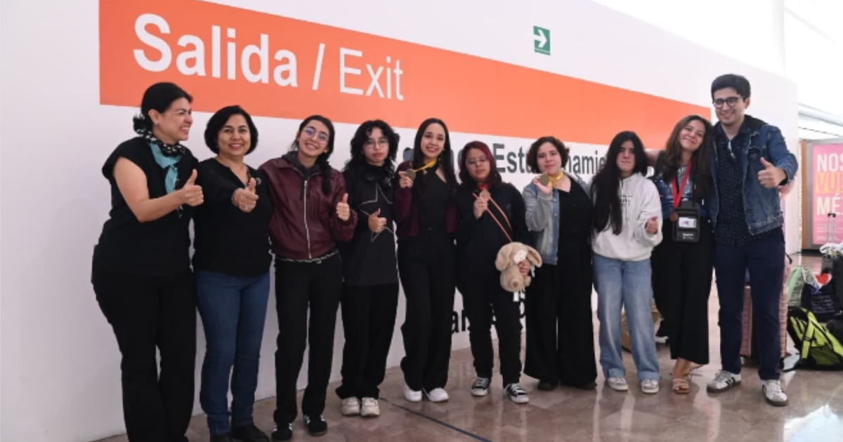Grupo de estudiantes de la UAS celebrando con pulgares arriba frente a un letrero de 'Salida / Exit'.