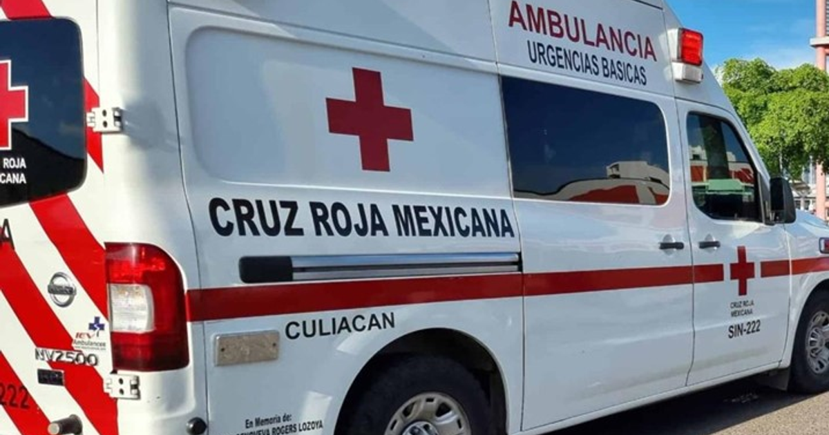 Ambulancia de la Cruz Roja Mexicana en Culiacán, estacionada en una vía con árboles y estructuras de fondo.
