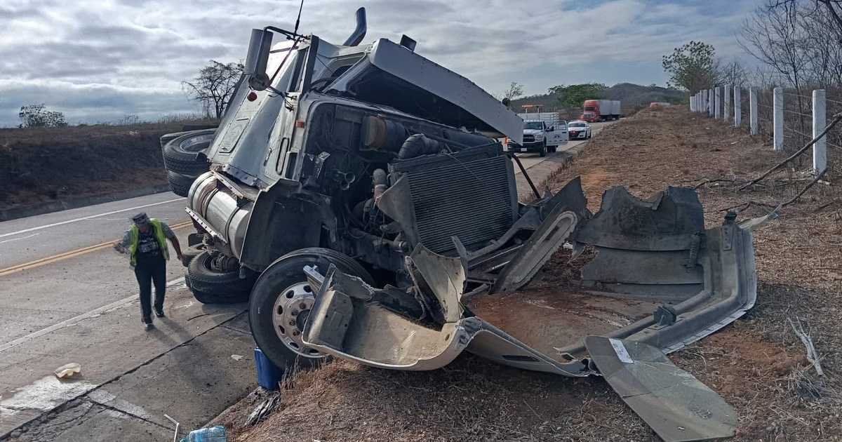 Camión volcado en la autopista Villa Unión-Tepic con persona en chaleco reflectante cerca.