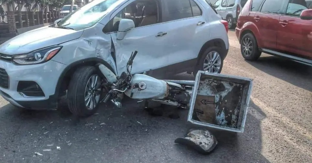 Accidente de tráfico entre un SUV blanco y una motocicleta en una vía urbana.