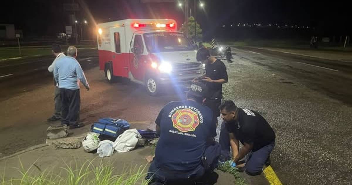 Ambulancia y personal de emergencia atendiendo a un herido en la carretera durante la noche.
