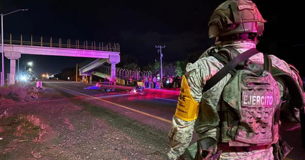 Militar vigilando escena de accidente en carretera México 15 con luces de emergencia y puente al fondo.