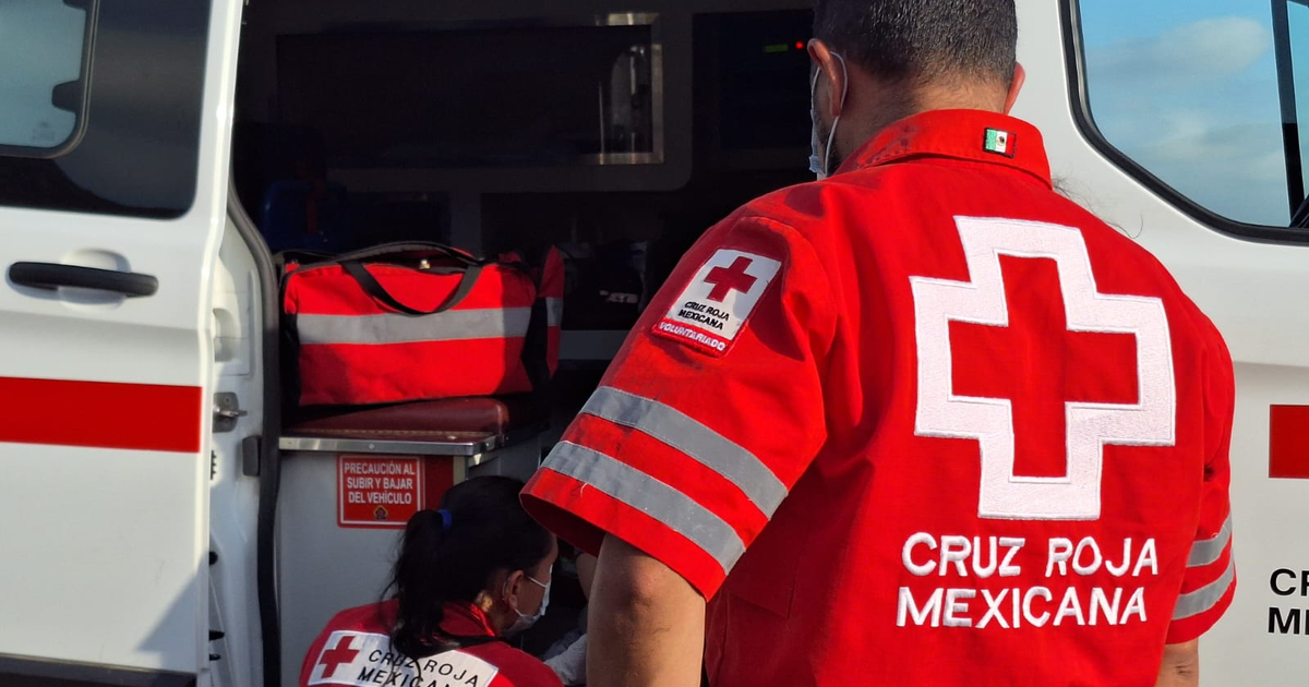 Personal de la Cruz Roja Mexicana en uniforme rojo dentro de una ambulancia con bolsas rojas y señal de precaución.