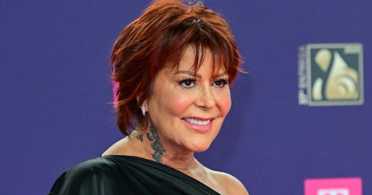 Alejandra Guzmán sonriendo en un evento con blusa oscura