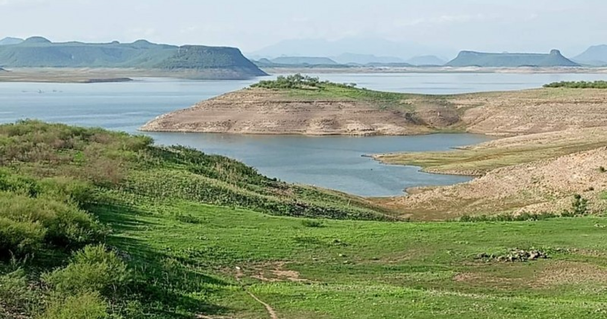 Vista panorámica de un embalse en Sinaloa con colinas y vegetación, bajo un cielo despejado.