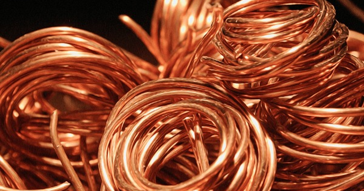 Bobinas de alambre de cobre con brillo metálico, desordenadas, reflejando el impacto de los aranceles en el mercado.