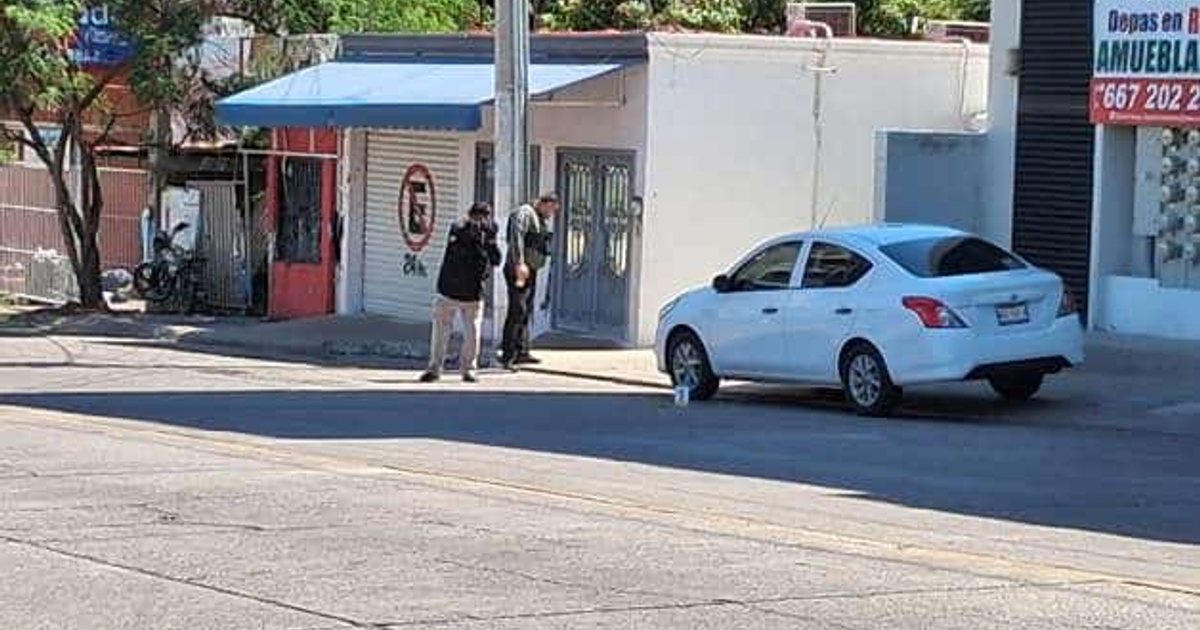 Calle en Nuevo Culiacán con coche blanco y personas observando el suelo, tras un ataque armado.