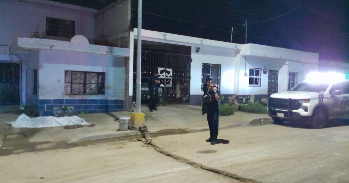 Escena nocturna con presencia policial en Mazatlán tras ataques armados, cuerpo cubierto y patrulla en la calle.