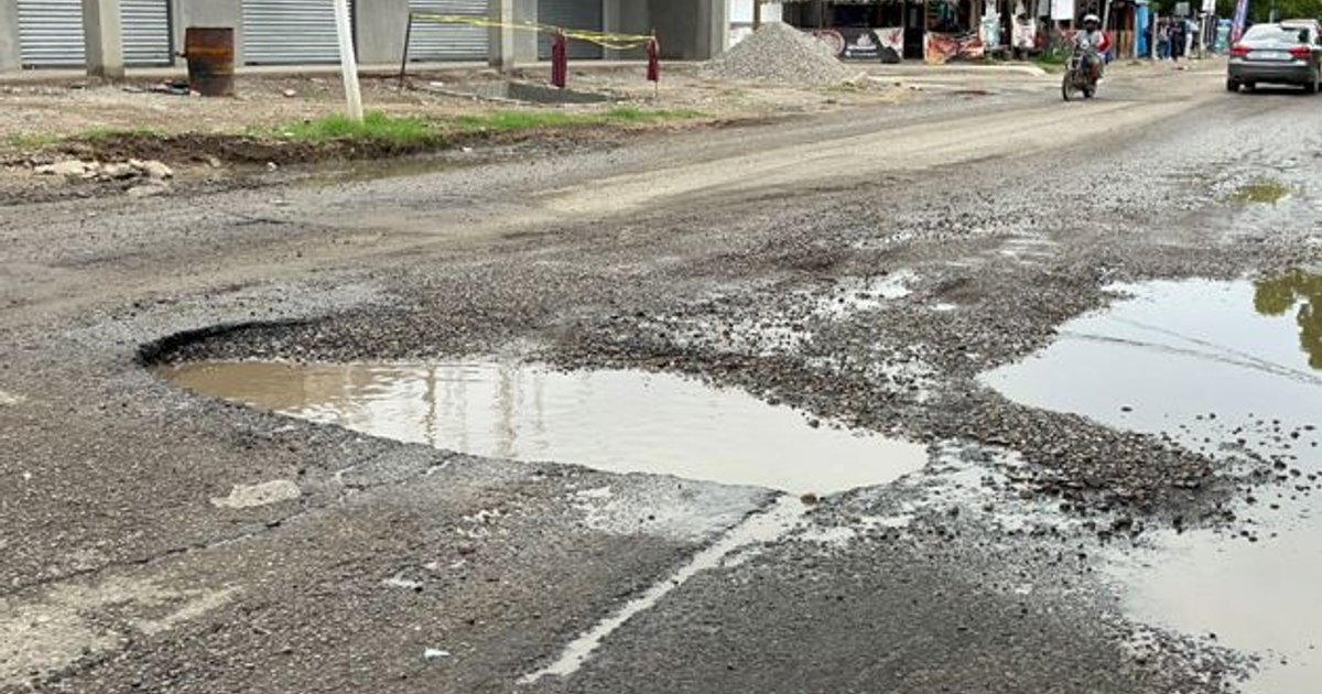 Callejón con bache y pavimento dañado en Mazatlán, reflejando problemas de infraestructura vial.