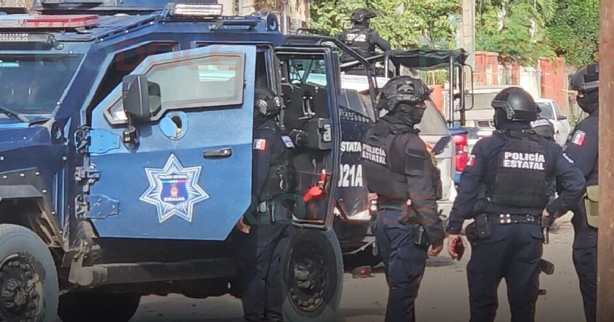 Policías estatales en alerta junto a vehículo policial tras enfrentamiento en Navolato
