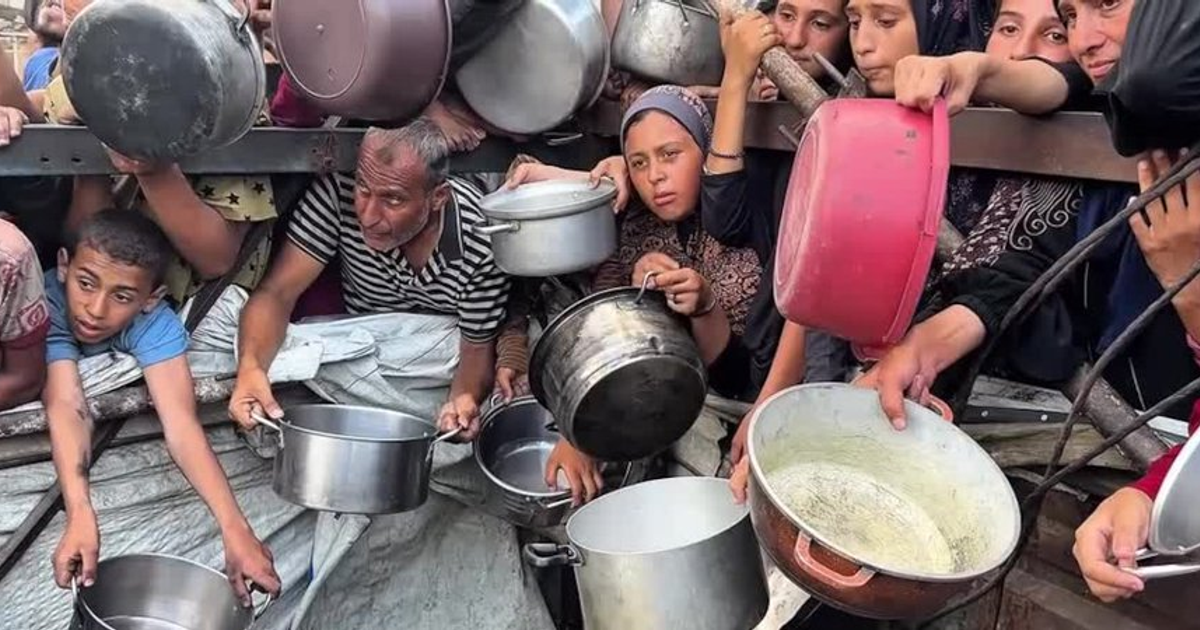 Personas en Gaza con ollas vacías en una cocina comunitaria improvisada, reflejando la crisis alimentaria.