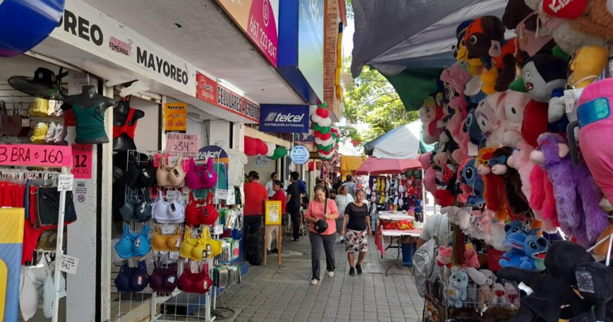 Calle comercial en Culiacán con tiendas y puestos, reflejando la crisis económica local.