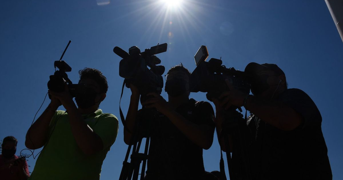 Siluetas de personas con cámaras bajo un cielo soleado, simbolizando la libertad de expresión.