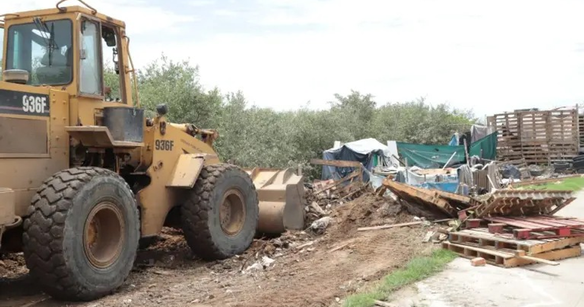 Cargadora en acción durante el desalojo en el Estero del Infiernillo, rodeada de escombros y restos de construcciones.