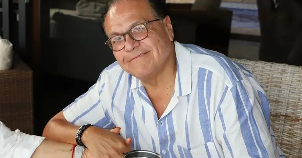 Persona con camisa de rayas blancas y azules sonriendo al aire libre