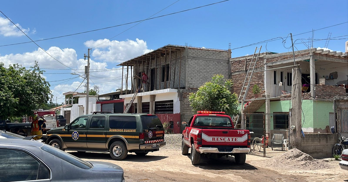 Camión de bomberos y camioneta de rescate en escena de emergencia en Guasavito, con trabajadores en un edificio en construcción.