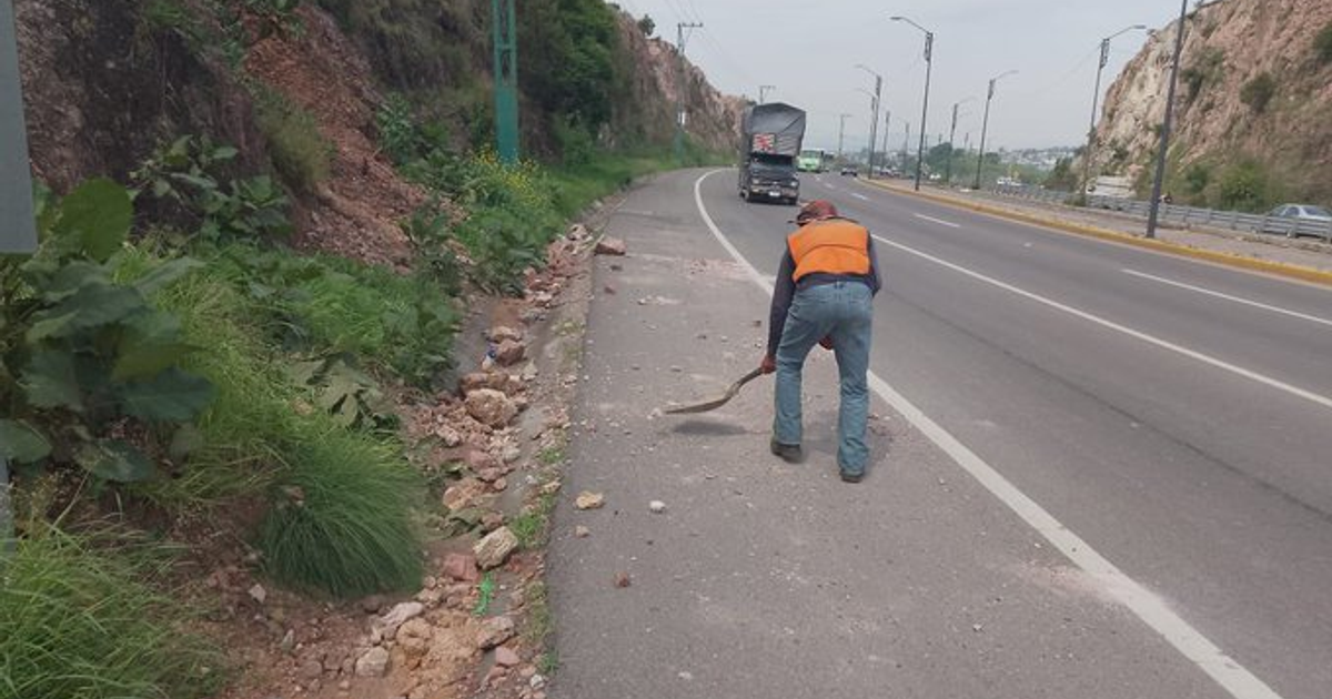 Trabajador limpiando escombros en carretera México 15 tras deslizamiento de tierra